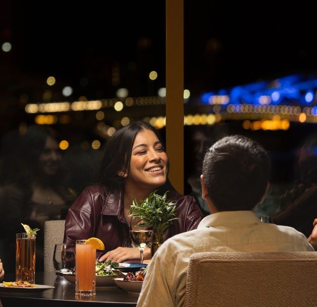 diners in Aura Waterfront Restaurant + Patio enjoying dinner with the city lit up in the background